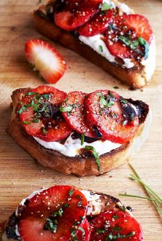 two pieces of toast with strawberries and cream on them sitting on a cutting board