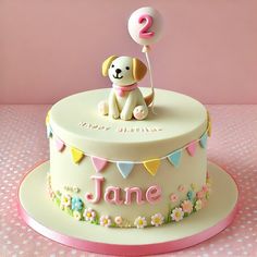 a birthday cake with a dog holding a balloon for the number two on it's top