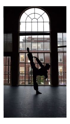 a person doing a handstand in front of a window with large arched windows