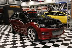 two cars are parked in a showroom with black and white checkered flooring