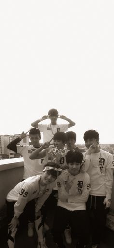 a group of young men standing next to each other on top of a building near the ocean