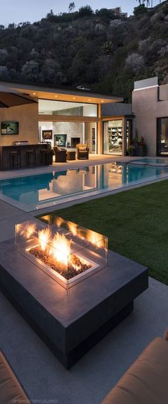 an outdoor fire pit in the middle of a backyard with a pool and patio furniture