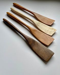 four wooden spoons lined up on a white surface