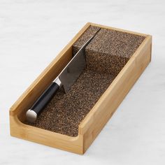 a cutting board with a knife in it on top of some sort of sand tray