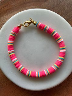 a pink bracelet with multicolored beads on a white plate