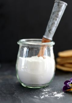 a glass jar filled with white powder next to a purple flower and corkscrew