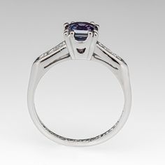 This gorgeous blue to purple color change sapphire engagement ring features a 1.16 carat no heat sapphire with Montana, USA origin that we sourced and set in a vintage platinum diamond mounting. The shoulders of the ring are each accented with three (3), channel set, round single cut diamonds, bordered with milgrain edging. The ring measures 6.2mm at the top, rises 6.3mm above the finger, tapering to 1.5mm wide and 1.3mm thick at the base of the shank. The ring is currently a size 5.75 and we offer complimentary resizing to fit. Classic Purple Sapphire Ring With Prong Setting, Purple Sapphire Ring With Brilliant Cut, Purple Tanzanite Ring With Brilliant Cut, Purple Sapphire Ring With Center Stone In Round Cut, Purple Sapphire Ring With Brilliant Cut For Anniversary, Classic Sapphire Rings In Purple, Classic Purple Sapphire Promise Ring, Purple Sapphire Ring With Center Stone, Round Cut, Purple Platinum Rings With Center Stone