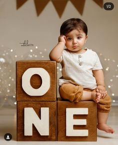 a baby sitting on top of wooden blocks that spell out the word one