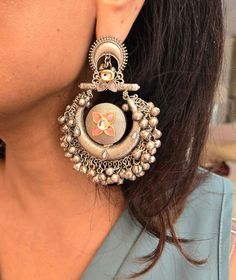 Statement silver boho ghungroo Kundan chandbaali earrings for a stunning look. Perfect for adding a unique and stylish touch to any outfit. Earring Dimensions:  Approximately 3.2 Inches Long  Approximately 2 Inches Wide  A Earring Weight is 1.3 oz All our products are crafted using traditional skills from our rich heritage. The manual nature of these crafts means that irregularities or variations are inherent in the handcrafting process. Festive Silver Chandelier Earrings With Tilla, Metal Chandbalis With Meenakari, Silver Tilla Jhumkas For Festival, Metal Chandbali Danglers With Meenakari, Silver Kundan Chandelier Dangle Earrings, Metal Meenakari Chandbali Danglers, Fusion Style Tilla Chandbalis Drop Earrings, Silver Metal Chandbalis For Festive Occasions, Chandbali Meenakari Danglers In Metal