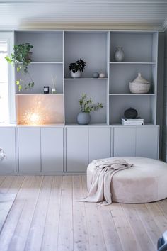 a living room filled with lots of furniture and plants on top of bookshelves