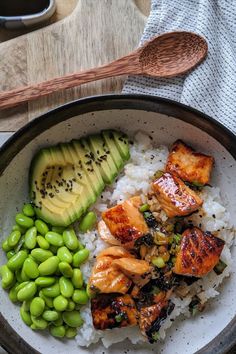 a bowl filled with rice, meat and vegetables next to an avocado slice