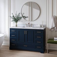 a bathroom vanity with two sinks and a round mirror above it, next to a bathtub