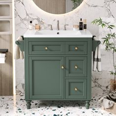 a bathroom vanity with green cabinetry and marble counter top, surrounded by greenery