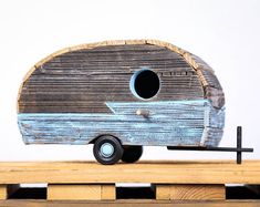 a toy trailer made out of wood sitting on top of a wooden table next to a white wall