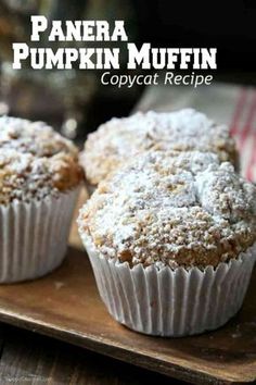 two muffins sitting on top of a wooden tray covered in powdered sugar