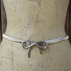 80s or  maybe 90s silver tone metal stretch belt with bow shaped buckle. Hook closure.   Fits 26 to 34" circumference Width is about 3/8" Good vintage condition with light signs of use and age such as a few subtle marks seen up close. Early 2000s Belts, Adjustable Silver Vintage Chain Belt, Vintage Metal Belt, Vintage Silver Adjustable Belt, Adjustable Silver Belt With Buckle Closure, Stretch Belt, Suspender Belt, Suspenders, Metallic Silver