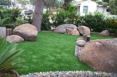 an artificial lawn with rocks and trees in the background