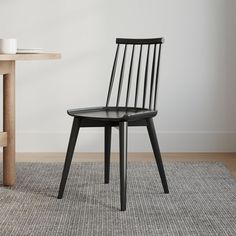 a black chair sitting on top of a rug next to a table