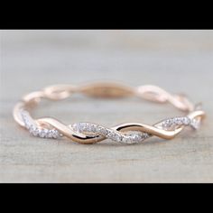 a rose gold wedding band with white diamonds in the shape of an intertwined ring