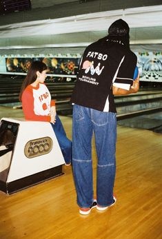 a man and woman standing next to each other in front of bowling alleys with their backs turned