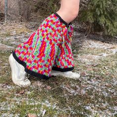 a person wearing colorful knitted pants and white shoes with trees in the back ground