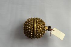 a gold beaded ball with a tag attached to it