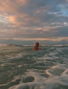 a woman is swimming in the ocean with her back turned to the camera and she's looking out into the distance