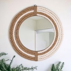 a round mirror hanging on the wall next to plants