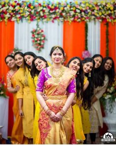 a group of women standing next to each other in front of an orange and yellow wall