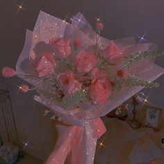 a bouquet of pink roses is wrapped in clear cellophane and sits on a table