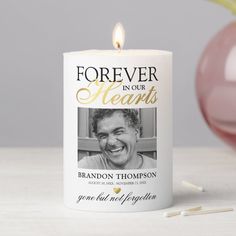 a candle with a photo on it next to an ornament that says forever in our hearts