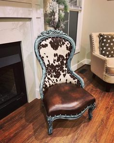 a cow print chair sitting in front of a fireplace