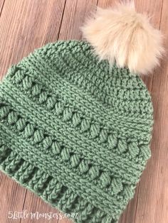 a crocheted green hat with a white pom - pom on top