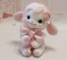 a small stuffed animal with a pink bow on its head sitting on a white surface