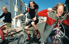 three women riding bikes down the street with their mouths open and one woman on her bike