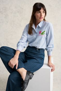 In a new shape for Blue Illusion, the Cotton Seersucker Shirt is a fun take on the classic striped shirt. Featuring a large pink tulip embroidered motif as well as contrast pink embroidery detailing, this shirt is crafted from ultra-comfortable cotton seersucker and will make any outfit pop. Embroidered Relaxed Fit Shirt For Spring, Spring Striped Relaxed Fit Blouse, Spring Floral Embroidery Relaxed Fit Shirt, Spring Blue Shirt With Striped Cuffs, Blue Shirt With Striped Cuffs For Spring, Spring Striped Collared Top, Preppy Top With Striped Collar For Spring, Spring Pinstripe Blouse With Striped Collar, Spring Pinstripe Collared Blouse