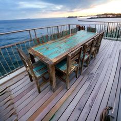 an outdoor table and chairs on a deck overlooking the ocean