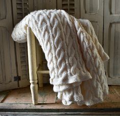 a white blanket sitting on top of a wooden chair