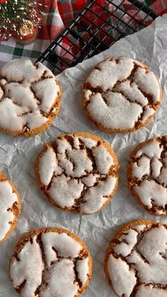 six cookies with white icing sitting on top of a piece of paper next to a christmas tree