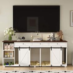 a tv mounted on the wall above a white entertainment center with sliding doors and drawers