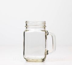 a glass jar with a handle is sitting on a white surface and the lid is empty