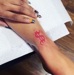 a woman's foot with a red dollar sign tattoo on her left leg and the word money painted on it