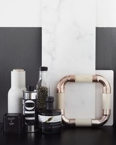 a black counter topped with bottles and other bathroom items next to a white frame on the wall