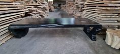 a black bench sitting in front of stacks of wood