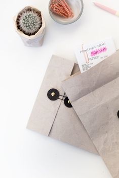 an open brown paper bag sitting on top of a white table next to a cactus