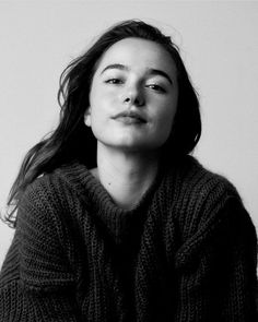 a black and white photo of a woman with her hair blowing in the wind, wearing a sweater