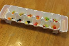 a plastic container filled with jelly beans on top of a wooden table