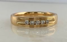 a yellow gold wedding ring with five diamonds on the bottom and side, sitting on a white surface