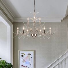 a chandelier hanging from the ceiling in a living room next to a staircase