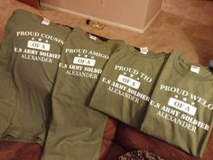 four green t - shirts with white letters on them sitting on top of a couch